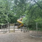River dart country park play area with yellow snake slide, wooden obstacle frame and roundabout